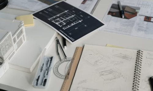 High-angle view of a desk with blueprints, sketches, and architectural tools.